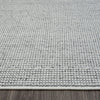 Grey flatweave rug with subtle textured geometric pattern and white edge trim on wooden floor.