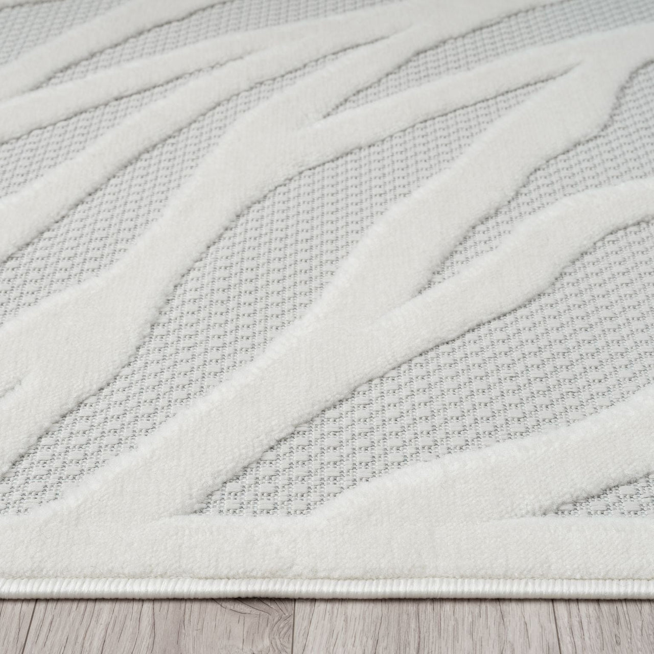 Ivory rug with raised geometric wave pattern on textured light gray polypropylene pile.