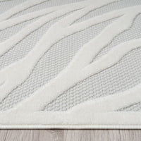 Ivory rug with raised geometric wave pattern on textured light gray polypropylene pile.