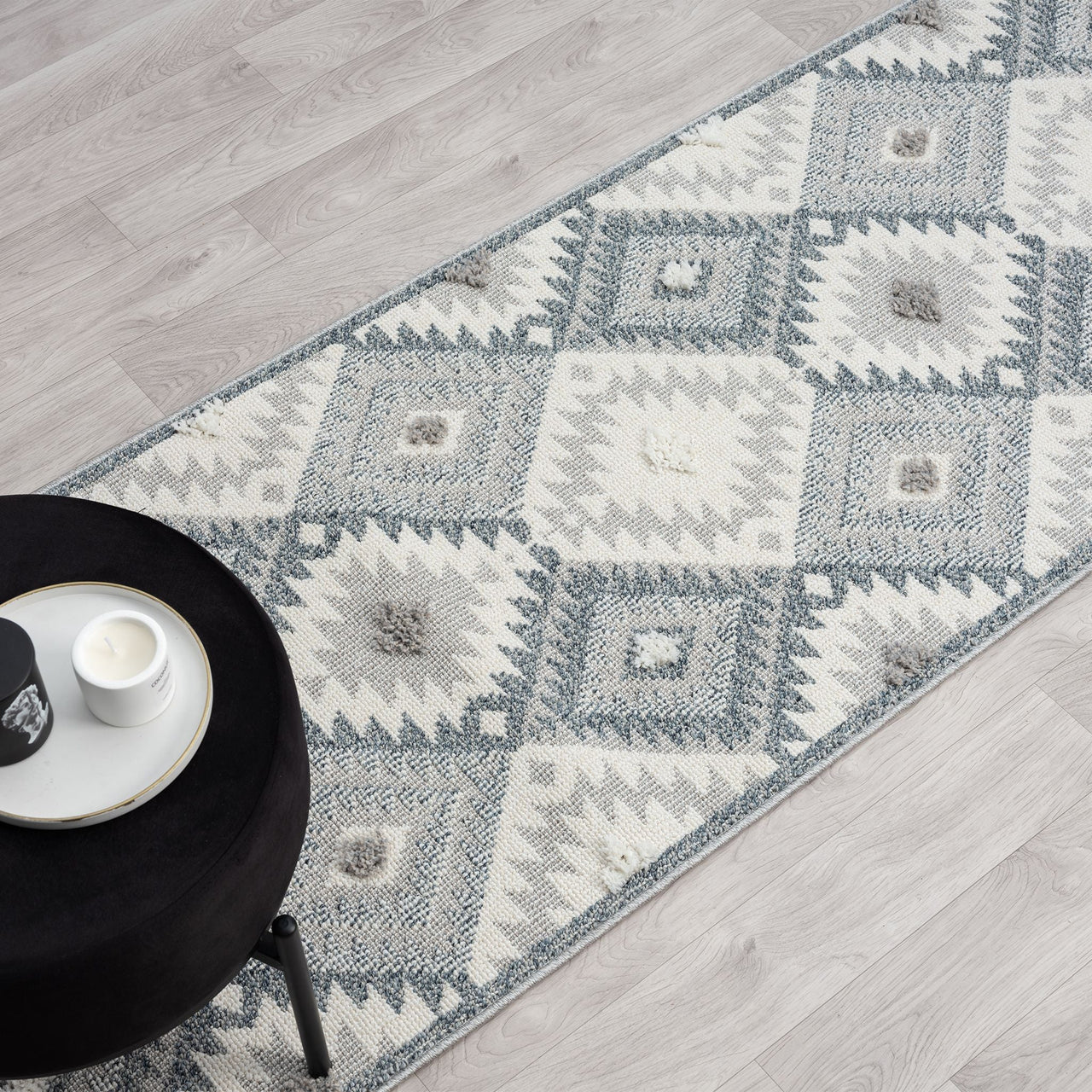 Grey and cream modern geometric patterned runner rug with textured pile and fringed edges on light wood floor.