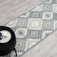 Grey and cream modern geometric patterned runner rug with textured pile and fringed edges on light wood floor.