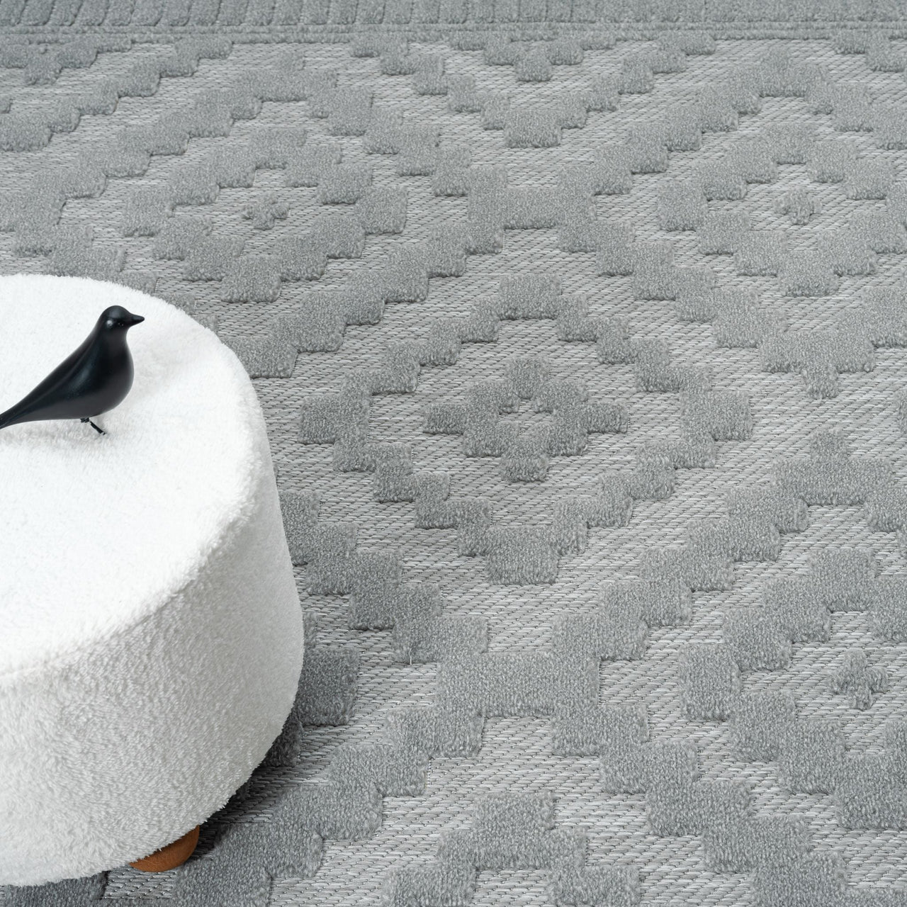 Grey geometric patterned modern rug with textured pile and diamond shapes.