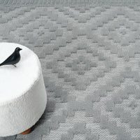 Grey geometric patterned modern rug with textured pile and diamond shapes.