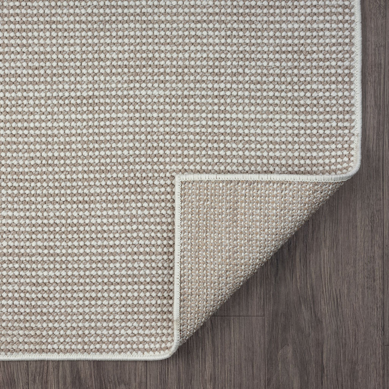 Beige flatweave rug with subtle geometric pattern and neatly finished edges on dark wood floor.