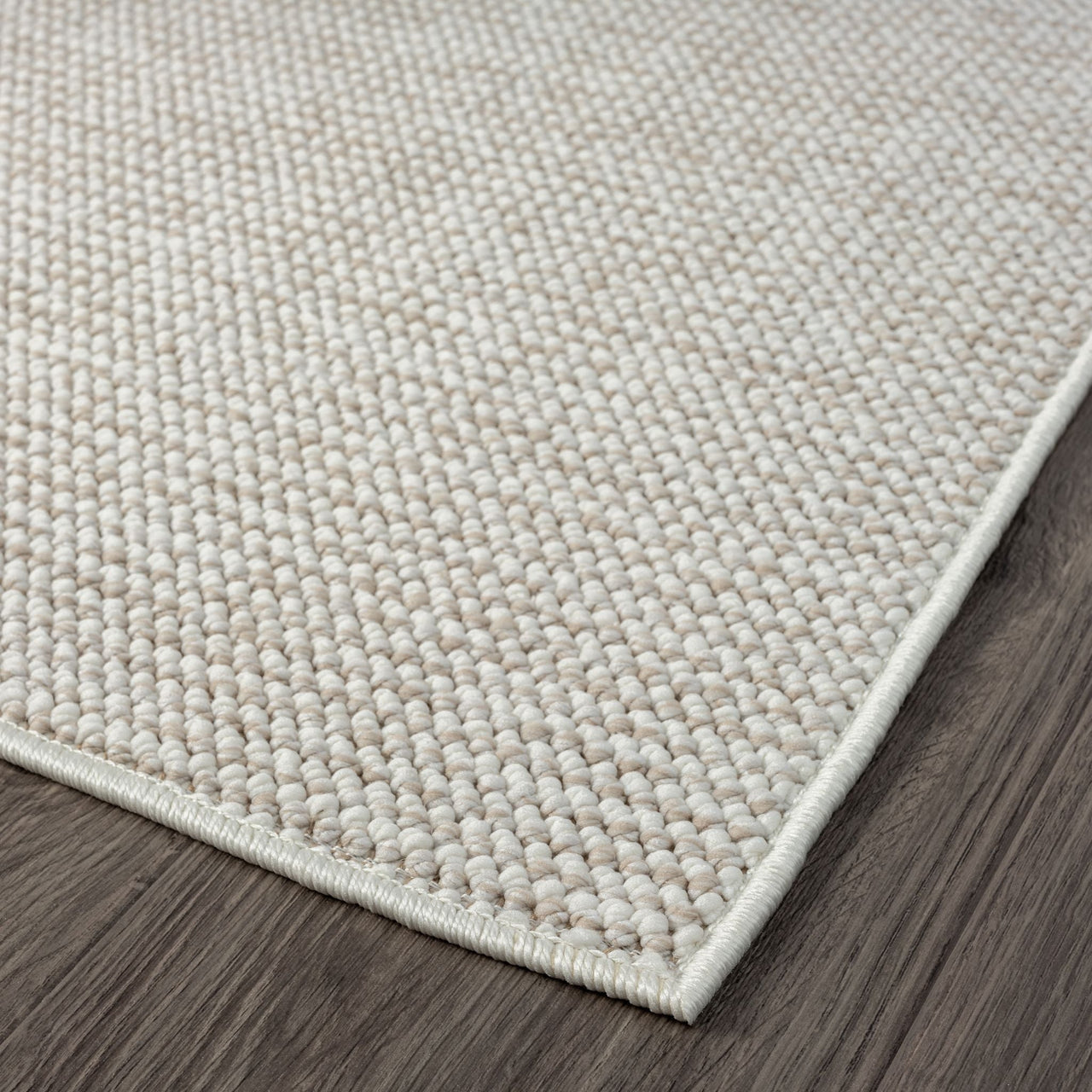 Beige flatweave rug with tight geometric pattern and clean, finished edges on wood floor.