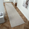 Beige flatweave runner rug with subtle geometric pattern on herringbone wood floor.