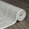 Rolled silver grey flatweave runner rug with subtle geometric texture on dark wood floor.