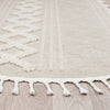 Beige and cream round rug with geometric textured pattern and fringe edges on light wood floor.