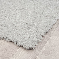 Grey modern shaggy rug with thick polyester pile on light wood floor.