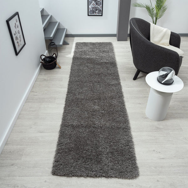 Grey shaggy runner rug with soft texture on light wood floor in modern hallway.