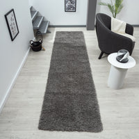Grey shaggy runner rug with soft texture on light wood floor in modern hallway.