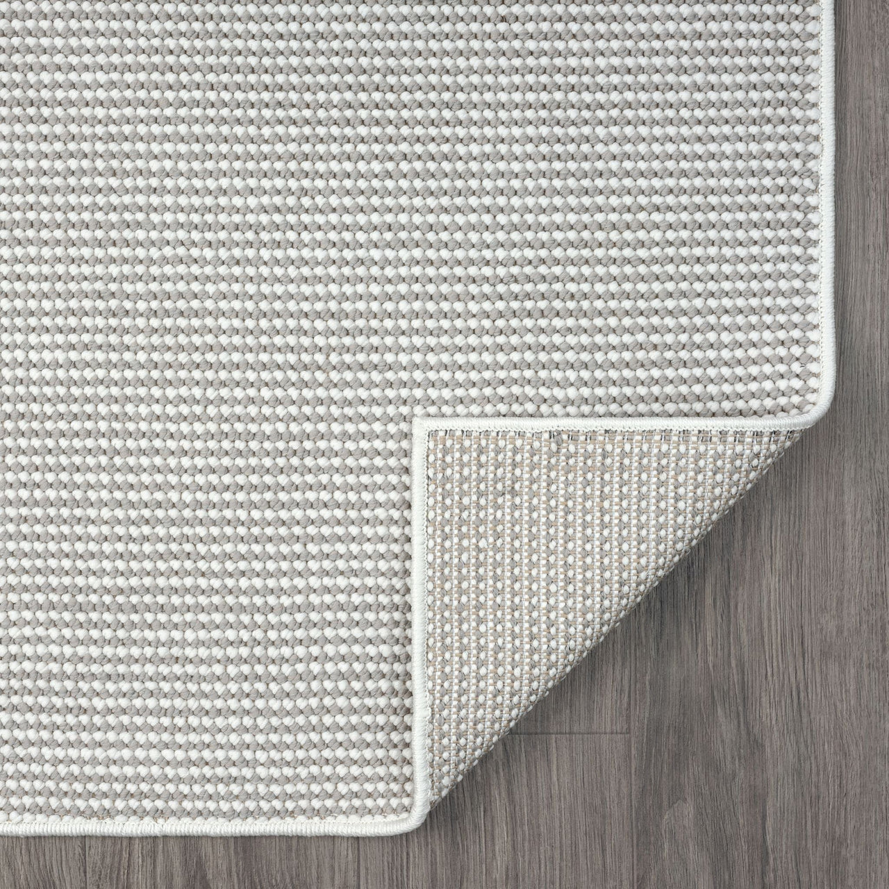 Grey flatweave runner rug with subtle geometric texture and clean white border on wood floor.