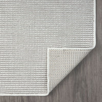 Grey flatweave runner rug with subtle geometric texture and clean white border on wood floor.