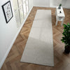 Beige flatweave runner rug with subtle geometric pattern on wood parquet floor.
