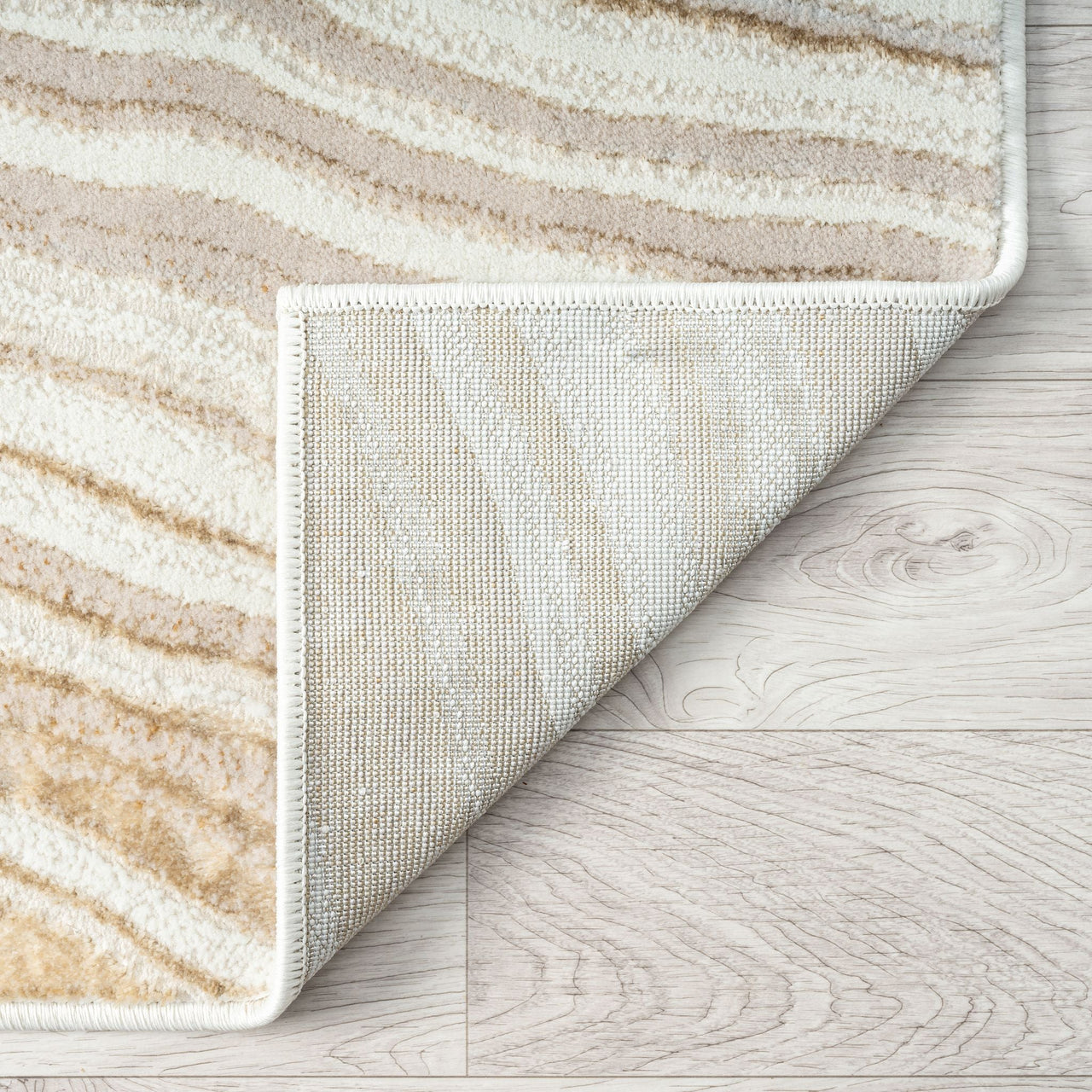 Close-up of a textured rug corner on a wooden floor