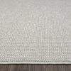 Beige flatweave rug with subtle geometric pattern and cream edging on hardwood floor.
