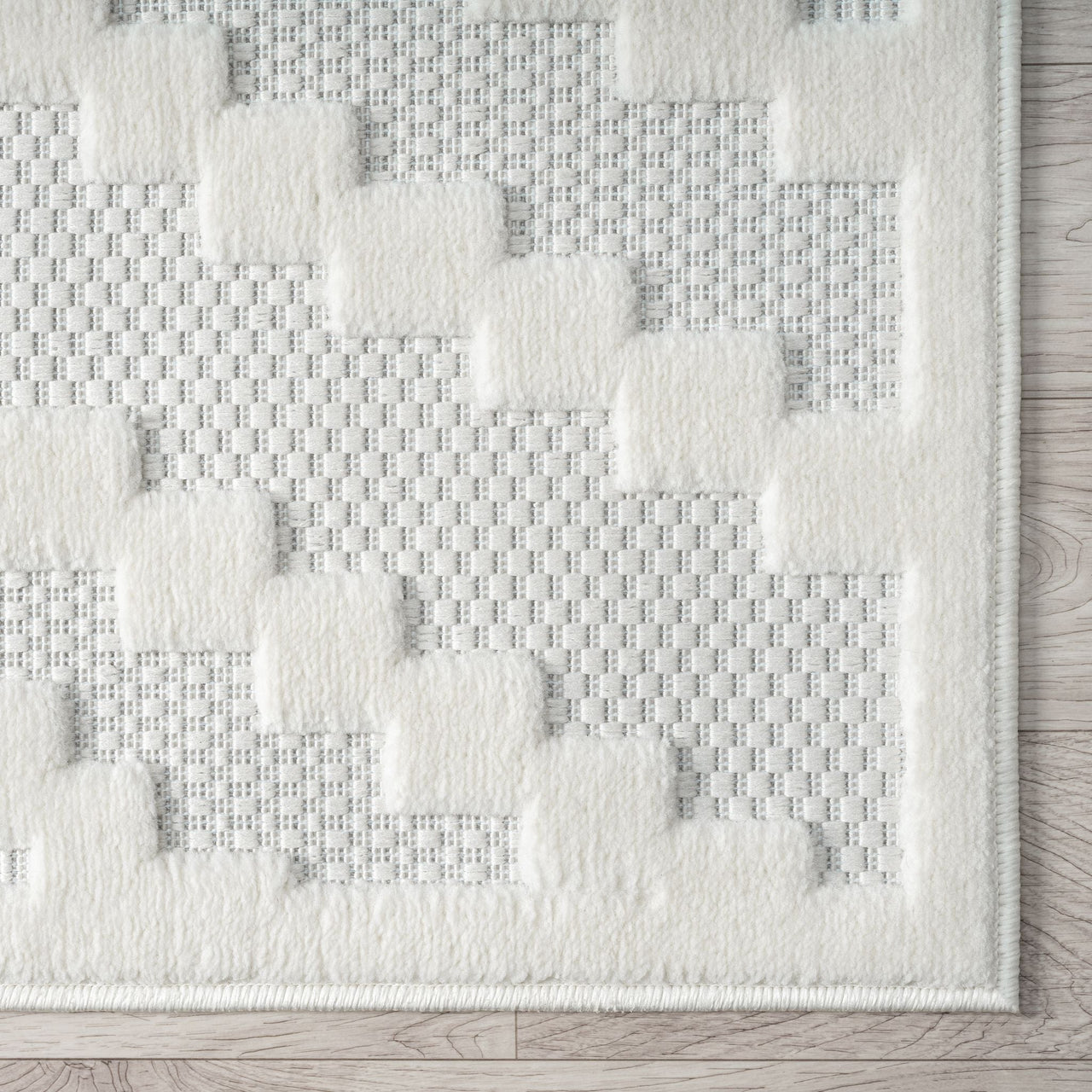 Cream rug with raised geometric squares and textured woven background in light neutral tones.