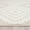 Beige and white Ceduna 2255 rug with textured geometric diamond pattern and fringe edges on wood floor.