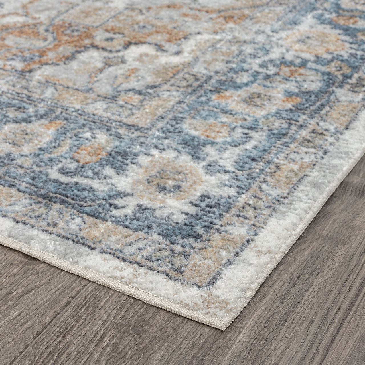 Blue and beige transitional rug with ornate floral and geometric patterns on a wooden floor.