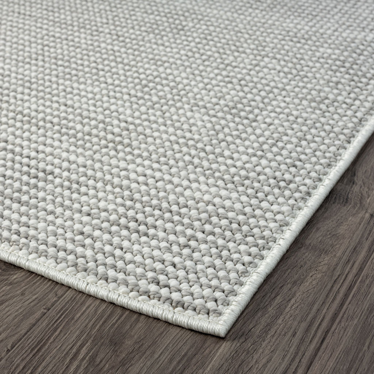 Silver grey flatweave rug with subtle textured weave and clean edge on dark wood floor.