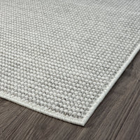 Silver grey flatweave rug with subtle textured weave and clean edge on dark wood floor.