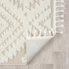 Beige and white modern geometric patterned runner rug with textured pile and fringed edges on light wood floor.