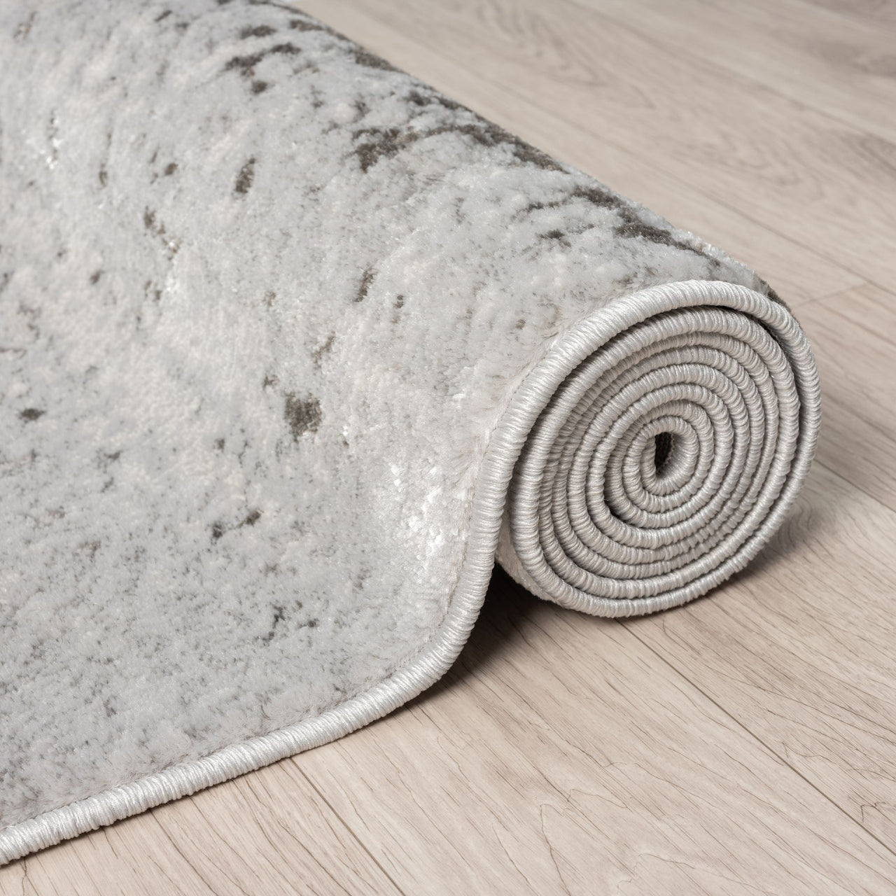 Rolled-up gray textured rug on a wooden floor
