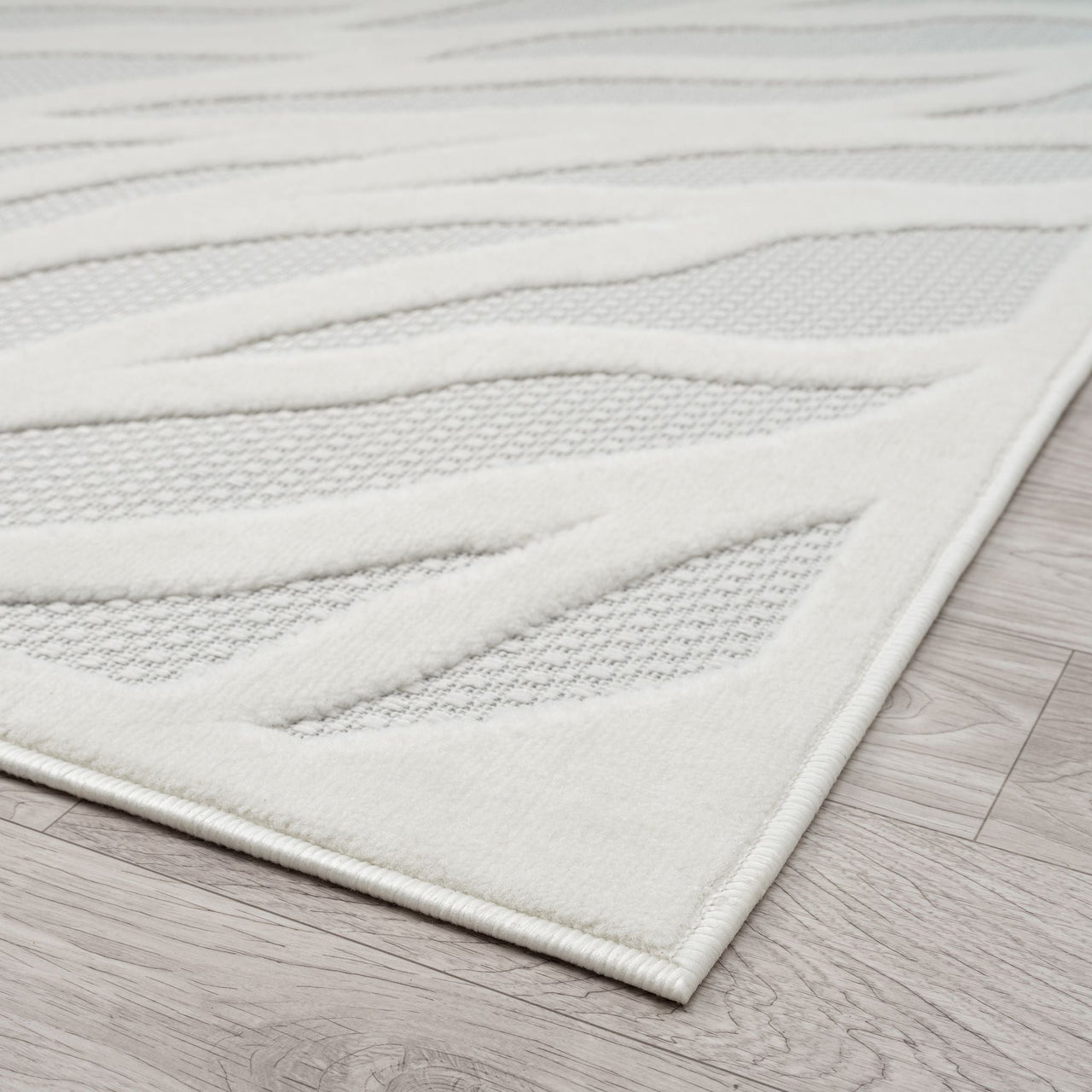Ivory runner rug with raised geometric pattern and textured polypropylene pile on light wood floor.