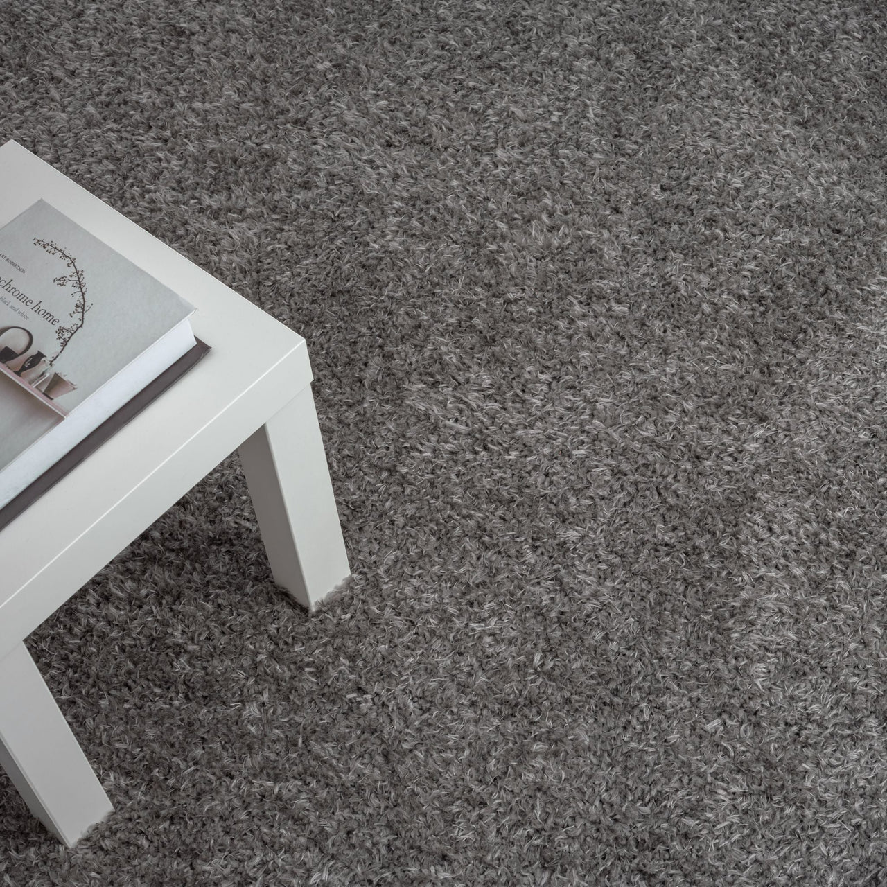 Grey shaggy rug with a soft, textured polyester pile beside a white table corner.