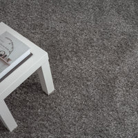 Grey shaggy rug with a soft, textured polyester pile beside a white table corner.