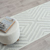 Cream runner rug with textured geometric diamond pattern on light wood floor.