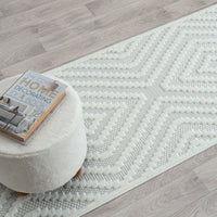 Cream runner rug with textured geometric diamond pattern on light wood floor.