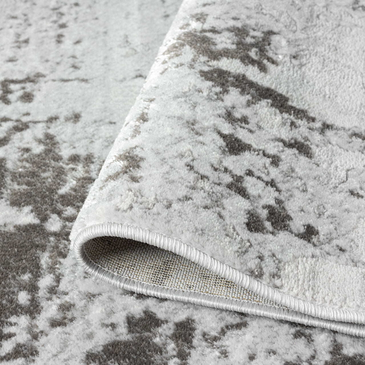 Close-up of a textured gray rug with an abstract pattern.