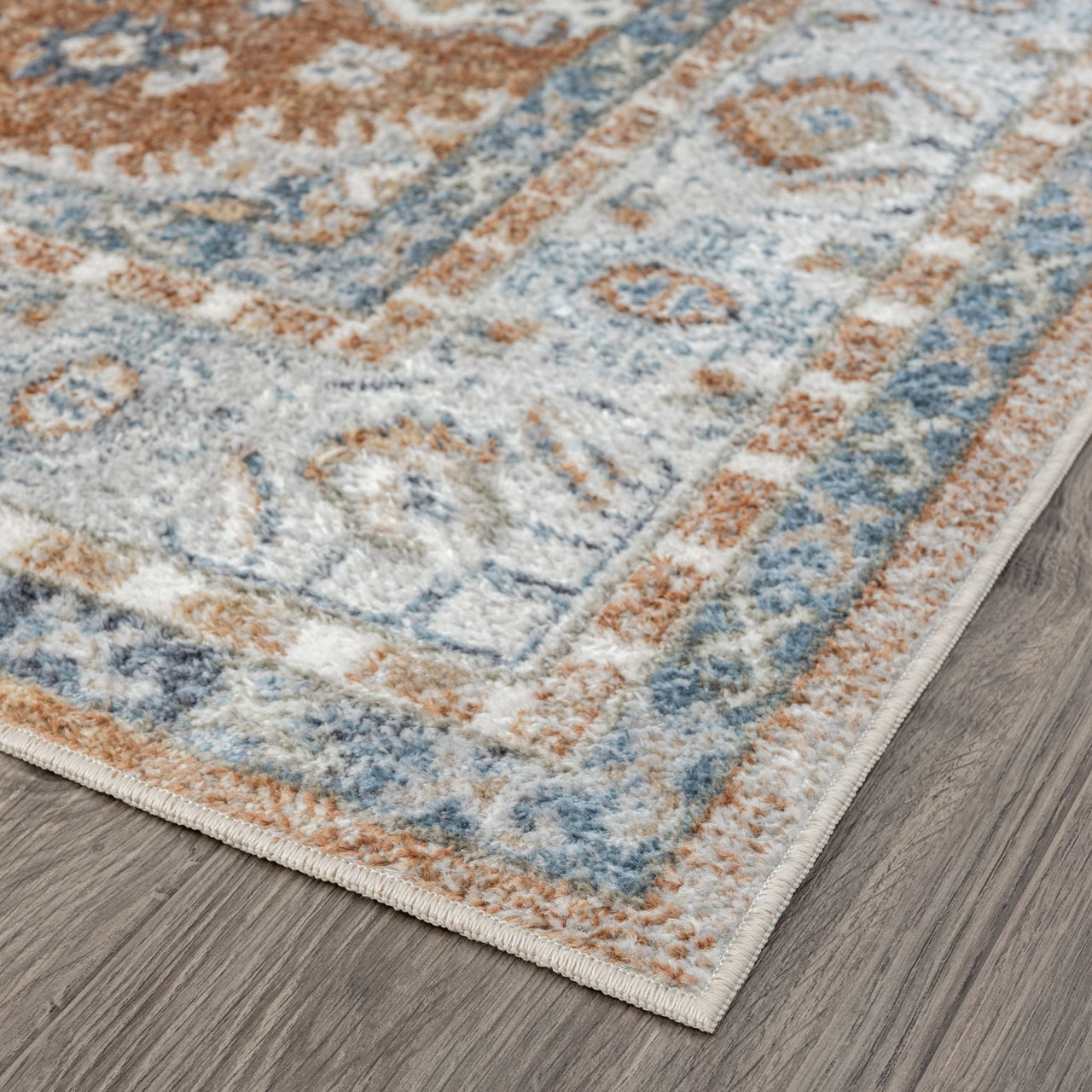 Terracotta multicolored transitional rug corner with blue and beige geometric patterns on hardwood floor.