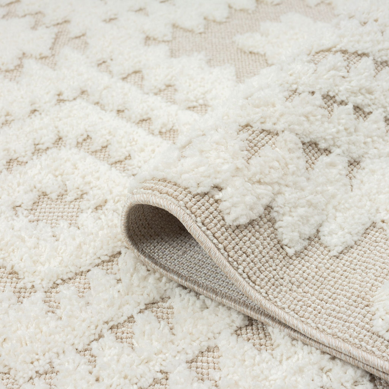 Beige and white geometric diamond patterned rug with textured pile and fringed edges.