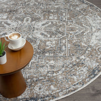 Round beige and gray patterned rug with distressed vintage design on dark wood floor next to wooden side table with cup and.