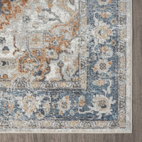 Blue, beige, and rust multi-colored transitional rug with ornate floral and geometric patterns and a textured edge.