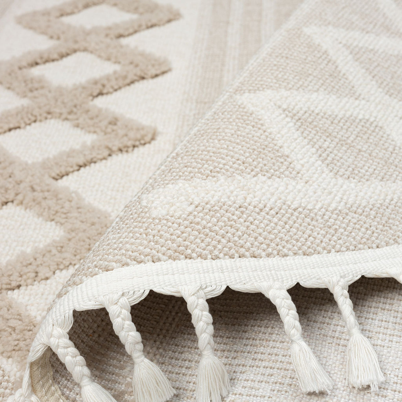 Beige and cream round rug with geometric patterns and tasseled fringes.
