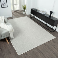Silver grey flatweave rug with subtle linear texture in modern living room setting.