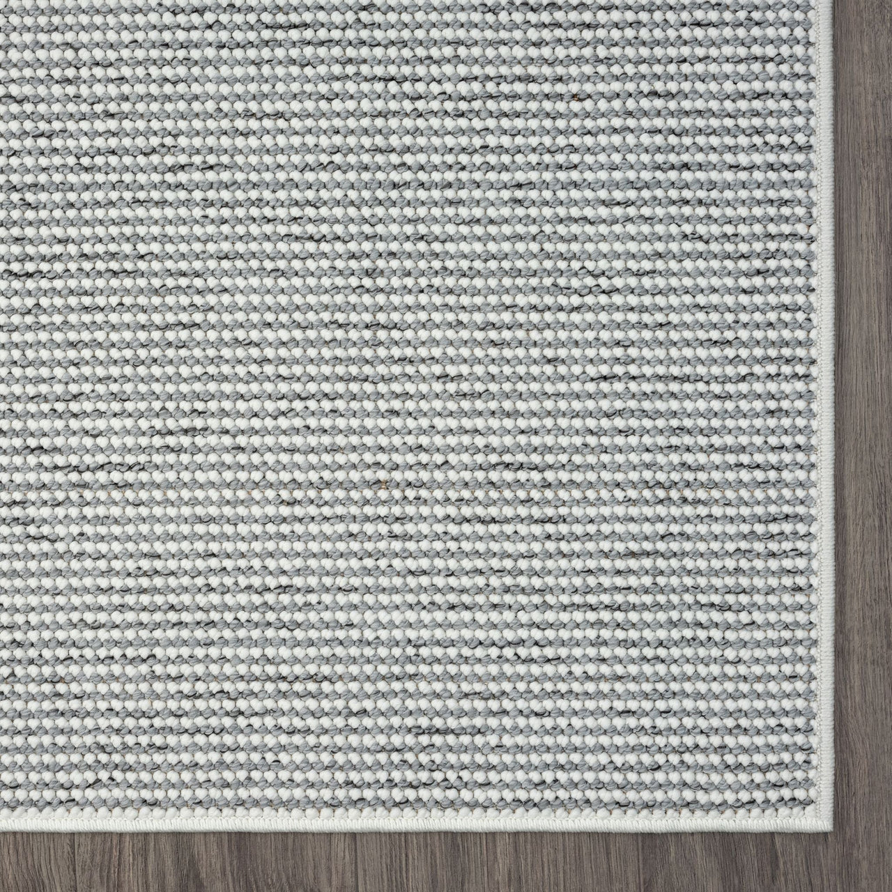 Grey flatweave rug with subtle textured pattern and clean stitched border.