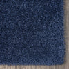 Navy blue shaggy rug with dense, soft polyester fibers on a wooden floor corner.