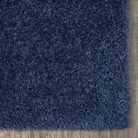 Navy blue shaggy rug with dense, soft polyester fibers on a wooden floor corner.