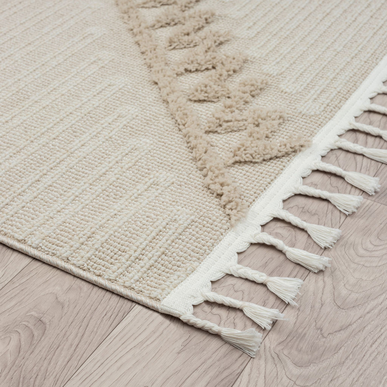 Taupe and beige runner rug with textured geometric pattern and white fringed edges on wood floor.