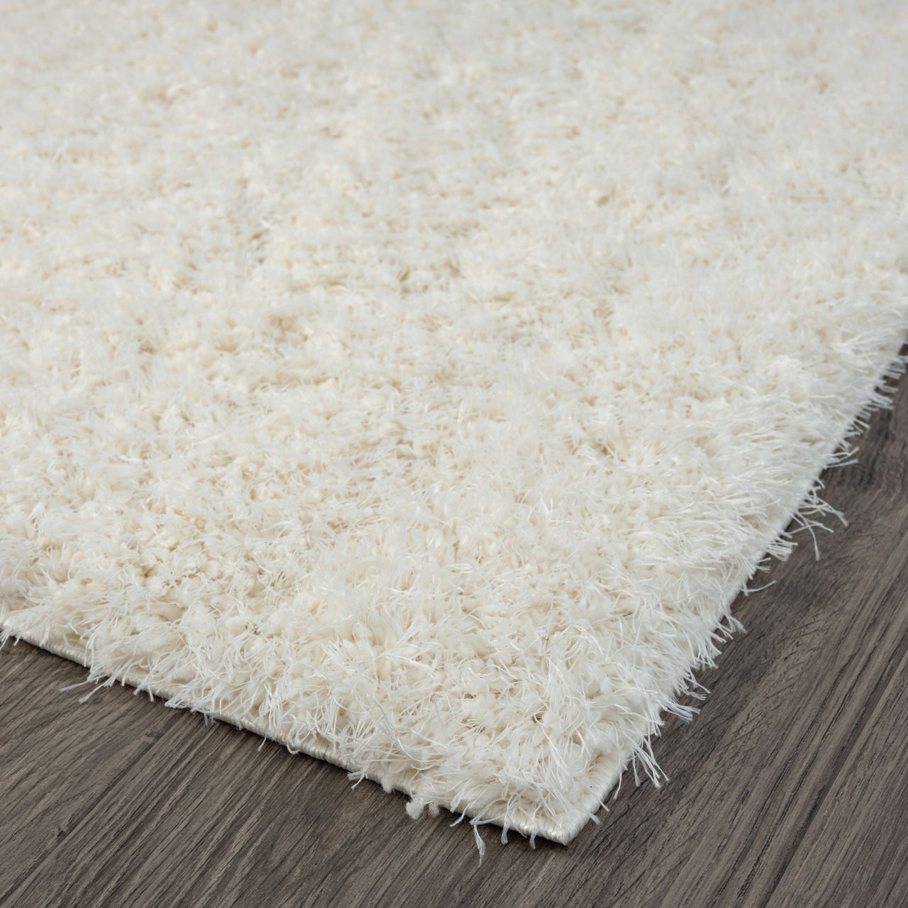 Cream-colored modern shaggy runner rug with thick polyester pile on dark hardwood floor.