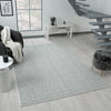 Grey flatweave rug with subtle geometric pattern in modern living room setting.