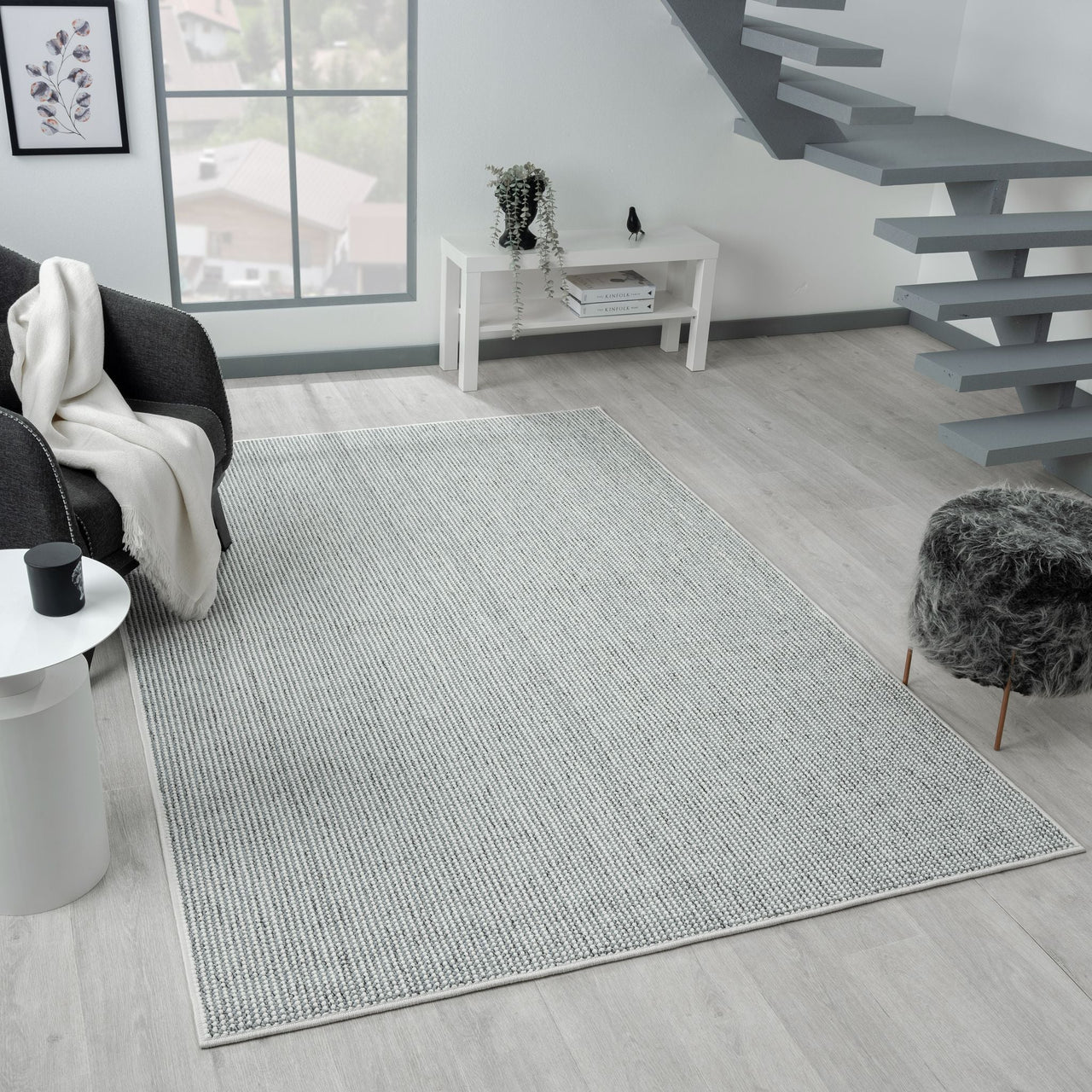 Grey flatweave rug with subtle geometric pattern in modern living room setting.