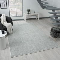 Grey flatweave rug with subtle geometric pattern in modern living room setting.
