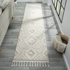 Beige and white runner rug with modern geometric diamond pattern and fringed edges on hardwood floor.