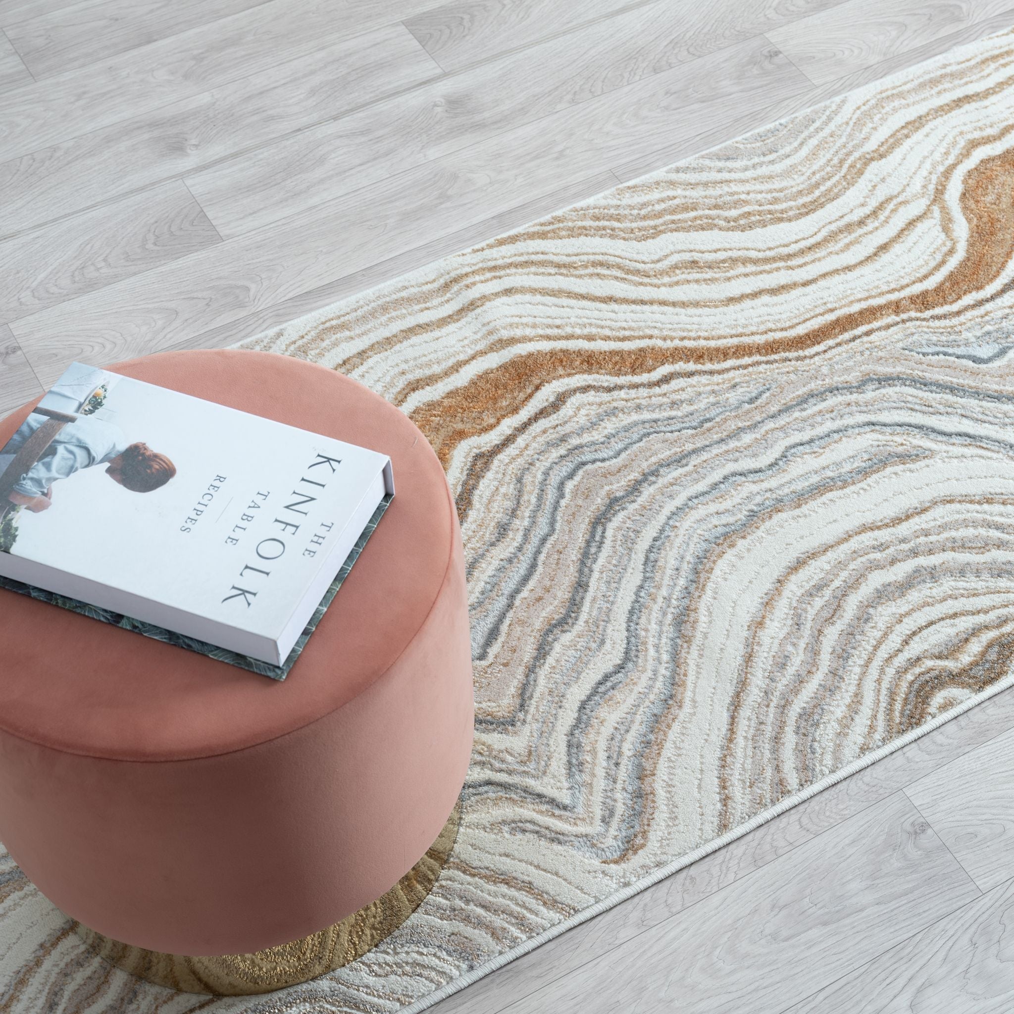 Pink ottoman with a book on a patterned rug