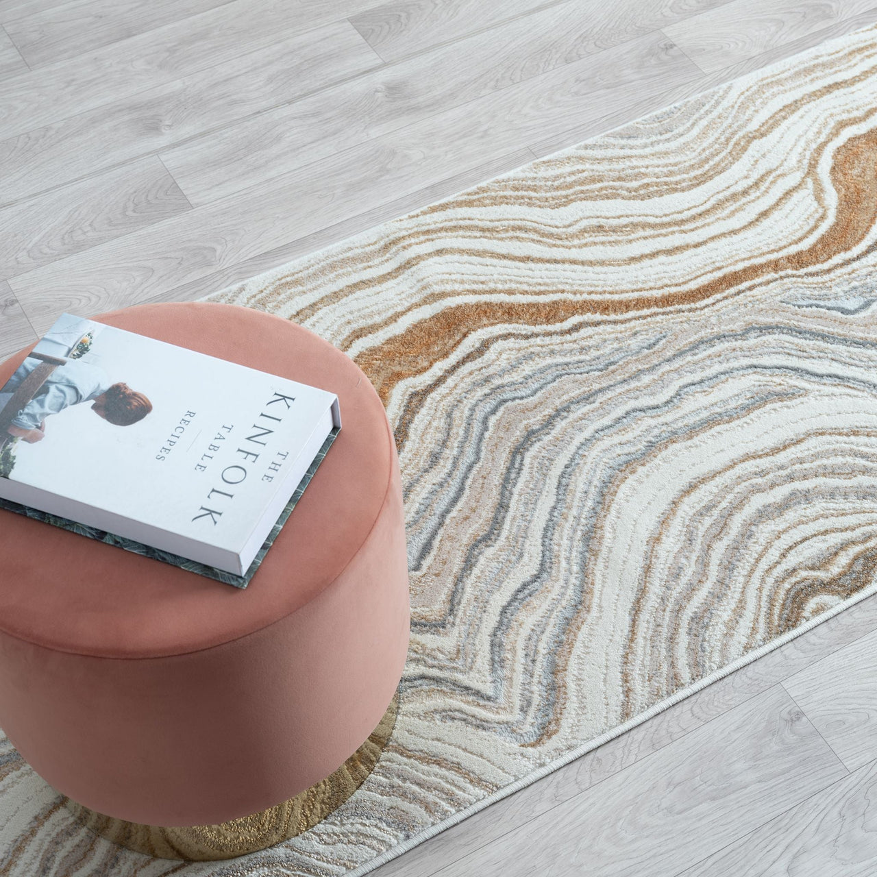 Pink ottoman with a book on a patterned rug